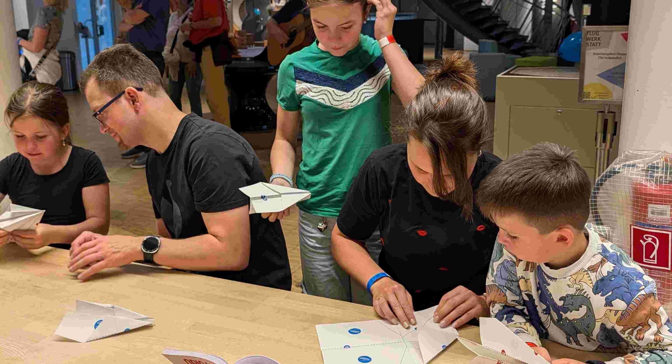Kinder und Erwachsene basteln einen Papierflieger